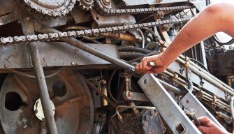 Combine machine service, mechanic repairing motor outdoors.