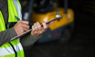 Male worker writing on clipboard in warehouse